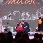 Stojący na scenie Paulina i Bartek Gruszeccy – muzyczne małżeństwo podczas swojego występu w towarzystwie gitarzysty - Kamila Szewczyka; widok z widowni