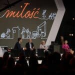 Cztery osoby siedzące na fotelach ustawionych na scenie, od lewej: Pan Tomasz Wolny, Pan Paweł Wdówik, Pani Anna Paruch oraz Pani Katarzyna Cimoch, widok z widowni