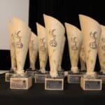 Trzynaście ustawionych na stole pamiątkowych statuetek Festiwalu