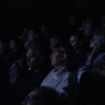 Siedząca w półmroku (w poświacie ekranu) publiczność podczas projekcji prezentowanych filmów konkursowych