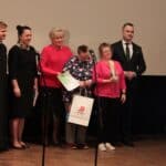 Od lewej stoją: ks. Paweł Zazuniak – Dyrektor Caritas Diecezji Siedleckiej, Pani Ewa Borkowska – Dyrektor Miejskiego Ośrodka Pomocy Społecznej w Białej Podlaskiej, Uczestnicy WTZ Łuków i Pan Jakub Semeniuk – Kierownik Warsztatów Terapii Zajęciowej w Białej Podlaskiej