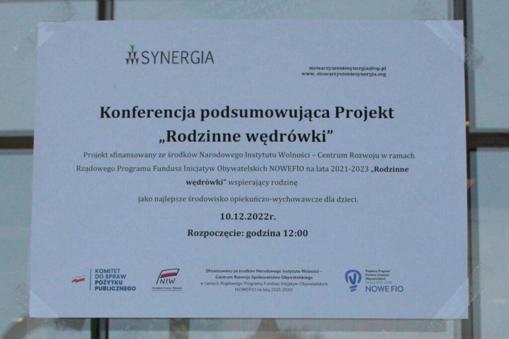 przyklejona do przeszkolonych drzwi kartka wielkości A4 informująca o konferencji podsumowującej Projekt „Rodzinne Wędrówki”
