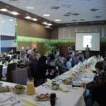 Siedzące przy zastawionych stołach rodziny z dziećmi uczestniczące w Projekcie „Rodzinne Wędrówki”