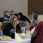 Rozmowy siedzących przy stole uczestników projektu “Rodzinne Wędrówki”