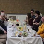 Radosna atmosfera wśród siedzących przy zastawionych stołach rodzin z dziećmi, uczestników Projektu „Rodzinne Wędrówki”