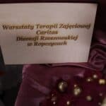 Drewniana tabliczka z napisem: „Warsztaty Terapii Zajęciowej Caritas Diecezji Rzeszowskiej w Ropczycach”