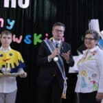 Od lewej: Członek Kapituły Orderu Uśmiechu trzymający tacę, na której znajduje się czerwona róża oraz puchar zawierający sok z cytryny, Marek Michalak (Kanclerz Kapituły Orderu Uśmiechu), Bożena Kazanowska (Nauczycielka SOWS dla Dzieci i Młodzieży Niepełnosprawnych im. Prof. Zofii Sękowskiej w Lublinie), uczniowie szkoły