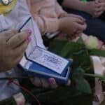 Zbliżenie na ręce Bożeny Kazanowskiej, trzymające legitymację, otrzymaną od Międzynarodowej Kapituły Orderu Uśmiechu