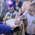 Uczniowie częstujący się okolicznościowymi ciasteczkami udekorowanymi we wzór Orderu Uśmiechu