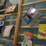 Dekoracja sali składająca się z książek dotykowych, zdjęć oraz maskotek, zawieszonych na drabinkach gimnastycznych