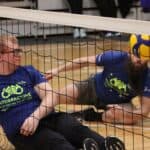 Dwóch zawodników za siatką patrzy na piłkę - zdjęcie oddaje dynamikę wydarzeń i ruch ciała zawodników