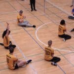 Zawodnicy Instytutu Pedagogiki w żółtych koszulkach, siedzący na boisku - cztery kobiety i dwóch mężczyzn