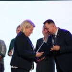 Pan Marek Wojciechowski (Wiceprzewodniczący Sejmiku Wojewódzkiego) podczas wręczania certyfikatu przedłużającego prawo do posługiwania się promocyjnym znakiem jakości „Zakup pro społeczny” w kategorii produkt, przedstawicielce Spółdzielni Socjalnej „Kuźnia Talentów” Mieniany, Pani Joannie Kuśmińskiej; w tle inni przedstawiciele nagrodzonych wcześniej instytucji.