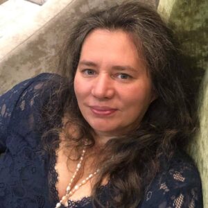 Maria Kierepka - kobieta w grantowej koronkowej sukience ze sznurem pereł, rozpuszczone długie włosy z usmiechem patrzy w obiektyw