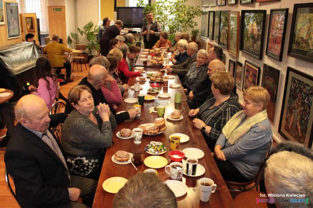 Członkowie Stowarzyszenia Osób Niepełnosprawnych „Otwarty Krąg” z Kurowa, siedzący po obu stronach zastawionego stołu