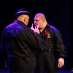 Dwaj ubrani na czarno odtwórcy ról męskich w spektaklu pt. „Siła miłości”