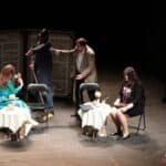 Scena ze spektaklu pt. „W kawiarni Zegarynka”: goście przy dwóch kawiarnianych stolikach