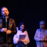 Przy mikrofonie stoi Przewodniczący Jury - Łukasz Witt-Michałowski, po jego lewej stronie stoją: Anna-Maria Sieklucka oraz Jolanta Toboła