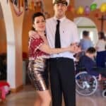 Mężczyzna w stroju kapitana tańczący z kobietą w lśniącej kreacji