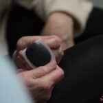 Zbliżenie na ręce, trzymające inteligentny transmiter noszony na skórze ramienia nad sensorem