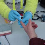 Nakłucie opuszka palca w celu wykonania pomiaru poziomu glukozy na stoisku wystawienniczym Lubelskiej Akademii WSEI