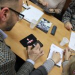 Pan Grzegorz instalujący aplikację na telefonie uczestniczki spotkania