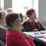 Kobiety siedzące przy stole, wsłuchane w prowadzony wykład