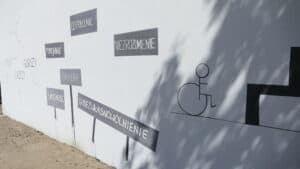 "Szary" mural z symbolami dyskryminacji - napisami: "inny", "gorszy", "słabszy", "pomijanie", "odtrącenie", "niezrozumienie", "bariery", "samotność", "ubezwłasnowolnienie"