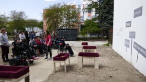 Uczestnicy happeningu przed "szarym" muralem z symbolami dyskryminacji