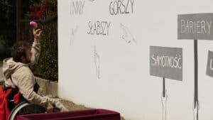 Pan Mateusz Pawelec – uczestnik WTZ rzucający balonik wypełniony farbą w "szary" mural