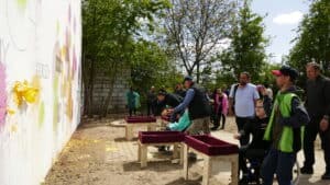 Uczestnicy rzucający w mural baloniki wypełnione farbą