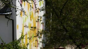 Mural pokryty plamami kolorowej farby w otoczeniu drzew