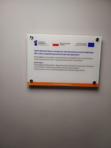 Umieszczona na białej ścianie tablica informacyjna Projektu