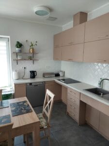 Pomieszczenie kuchenne z zabudową w kolorze beżowym i stołem z krzesłami