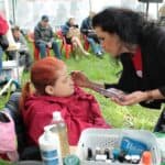 Pracownik wykonujący makijaż Uczestniczce pikniku siedżacej na wózku