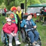 Pamiątkowa fotografia uczestników na wózku w towarzystwie opiekunki oraz animatorki w stroju klauna