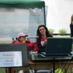 Uczestniczka na wózku i pracowniczka ŚDS Mozaika śpiewają do mikrofonu