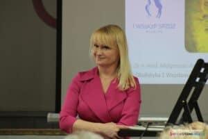 Pani dr n. med. Małgorzata Kowal - uśmiechnięta, długowłosa blondynka ubrana w różową sukienkę