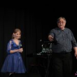 Na scenie od lewej stoi Pani Agnieszka Zarzycka oraz Pan Marek Kowal, trzymający w ręku płytę CD, podczas zadawania pytania w mini-konkursie