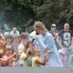 Animatorka w stroju Elzy wśród dzieci, na które spada sztuczny śnieg