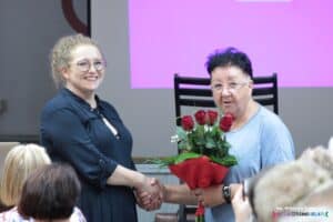 Pani Elżbieta Sagan wręcza bukiet czerwonych róż Pani Ewelinie Stachel-Miedzianowskiej