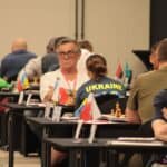 Pierwszy dzień rozgrywek; zawodnicy siedzący przy stolikach w sali konferencyjnej podczas partii szachowych