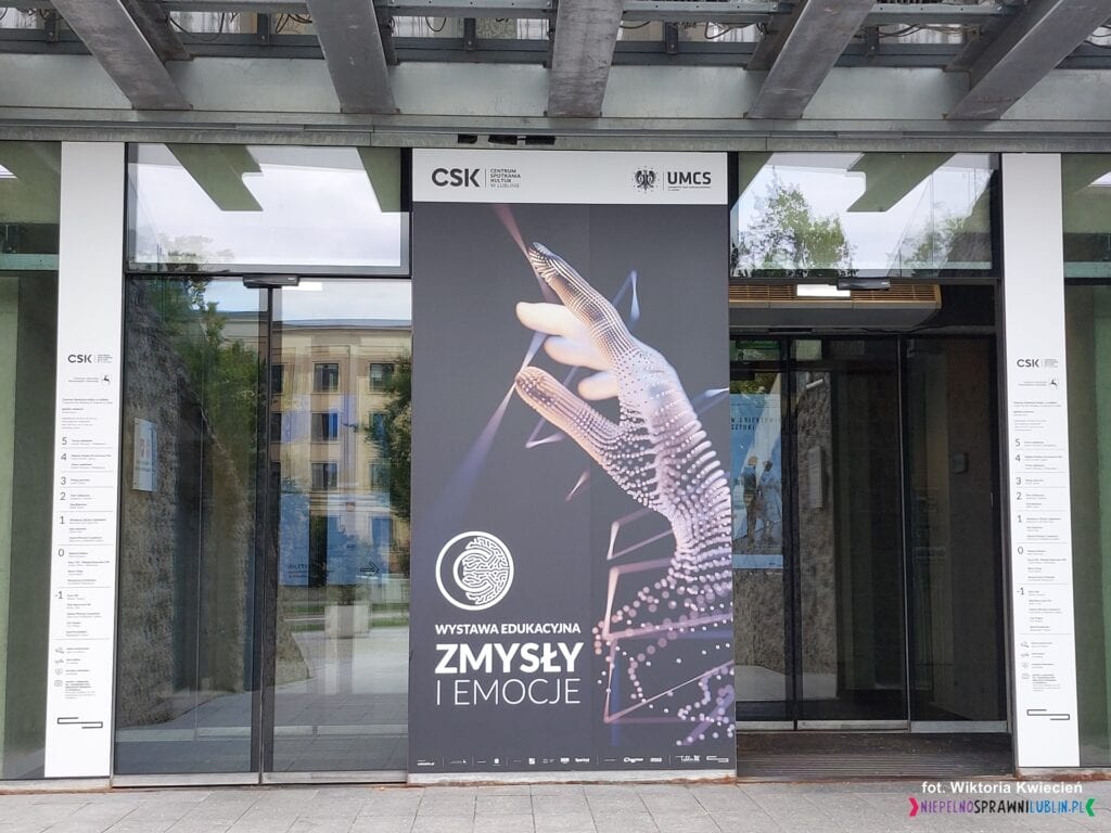 Wejście do Centrum Spotkania Kultur od Placu Teatralnego; drzwi rozsuwane z planszą wystawy "Zmysły i emocje"