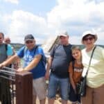 Grupa osób na tarasie widokowym, w tle widoczne błękitne niebo