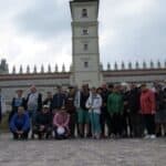 Grupa osób na tle bramy wjazdowej do zamku