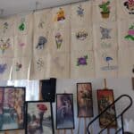 Wystawa prac wszystkich uczestników projektu: wiszące na ścianie torby ręcznie malowane i haftowane, na sztalugach obrazy wykonane techniką haftu diamentowego
