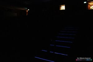 Sala widowiskowa pogrążona w ciemności; widok na podświetlone schody