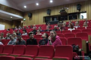 Uczestnicy siedzący na widowni w oczekiwaniu na rozpoczęcie spektaklu