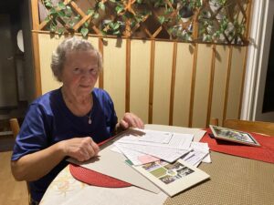 Helena Suchocka, starsza pani z siwymi loczkami i łagodnym spojrzeniem siedzi przy stole i przegląda własnorecznie zapisane notatki