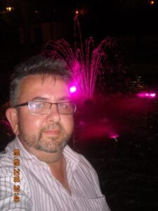 Jarosław Chabros na tle fajerwerków - mężczyzna w średnim wieku w okularach i wąsach i lekką brodą